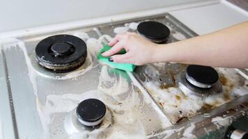 Scrubbing the stove top hard. A hand scrubs a dirty stove top with a cloth, removing grease and grime in a kitchen setting during daylight. video
