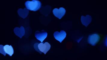 Blue hearts glowing softly in darkness. Glowing blue hearts float gently in a dark setting, creating a dreamy and serene atmosphere during nighttime. video