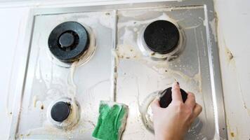 Cooktop covered in foam. A dirty cooktop is covered in cleaning foam, with a green sponge on it, indicating deep cleaning in progress. video
