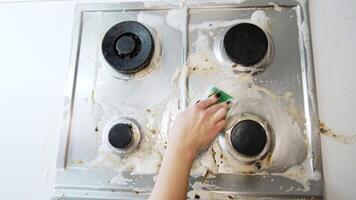 Scrubbing stove with soap. A hand scrubs a stove top with soap and sponge while removing grease and grime, showing the cleaning process in action. video