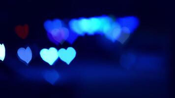 Nighttime lights, heart shapes. Bright heart shapes emerge from blurred lights in a dark setting, creating a festive and romantic atmosphere. video
