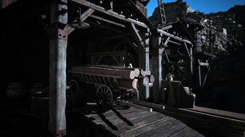 Rustic wooden cart loaded with logs near mining structures at dusk video
