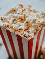 Close up of freshly popped popcorn in a classic red striped container for movie night photo