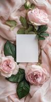 Elegant blank white greeting card amidst pink roses and silk fabric for romantic occasions photo