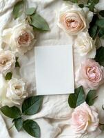 Dreamy and sophisticated flat lay with blank invitation surrounded by elegant roses and greenery photo