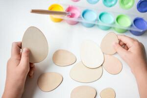 Child creating wooden Easter eggs with colorful paints for art project photo