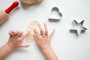 Child hands crafting with dough and cookie cutters in kitchen setting photo