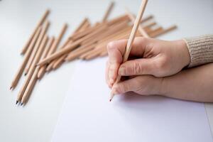 Close up of hands drawing with colored pencils on white paper photo
