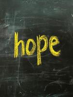 Hope written in bright yellow chalk on blackboard for inspirational design photo