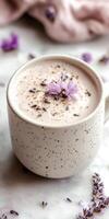 Creamy lavender latte in matte white ceramic cup with floral photo