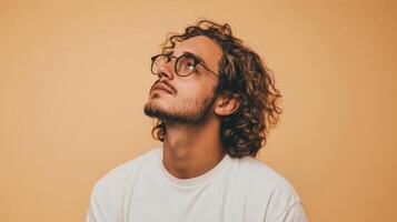 Portrait of a young man with curly hair and glasses looking up photo