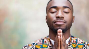 A young man peacefully prays with clasped hands photo
