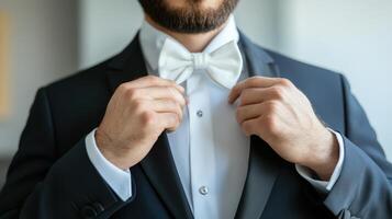 Man adjusting his white bow tie in a dark suit photo