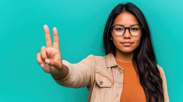 A young woman with glasses and a jacket is making the peace sign photo