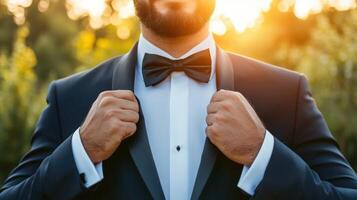 Man adjusting his tuxedo bow tie outdoors photo