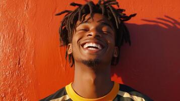 Joyful Young Man With Dreadlocks Against Orange Wall photo