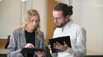 Professional workers busy discussing and reviewing about work report in digital device and files in clipboard. video