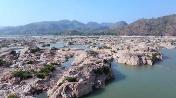 view of a rocky riverbed with scattered pools of water during the dry season, surrounded by mountains and sparse vegetation. The unique landscape highlights the effects of seasonal water levels video