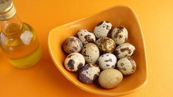 Colorful mixed quail eggs displayed in a bowl on orange background video