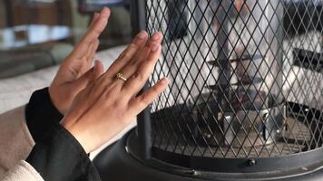 Hands warming up near a heat source in a cozy setting video