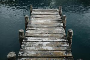 Rustic Wooden Dock Over Calm Blue Lake Water with Weathered Planks and Peaceful Outdoor Setting photo