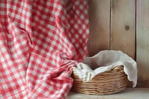 Red And White Checkered Fabric Drape With Empty Woven Basket On Rustic Wooden Background photo