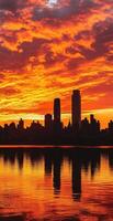 Dramatic Fiery Sunset Over City Skyline Reflecting On Calm River With Vibrant Clouds In Background photo