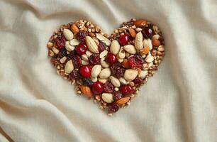 Heart Shaped Nuts And Dried Fruits With Cherries On Beige Fabric Background For Healthy Living Concept photo