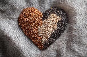 Heart Shaped Arrangement of Multicolored Grains and Seeds on Rustic Burlap Fabric Background photo