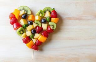 Heart Shaped Mixed Fruit Arrangement with Strawberries Kiwi Mango on Wooden Background photo