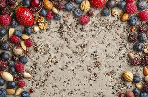 Assorted Fresh Berries Almonds Walnuts on Textured Gray Background with Crumbled Seeds and Spices photo