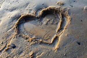 Heart Shape Drawn in Wet Sand with Water on Shoreline at Sunset Reflecting Golden Light photo