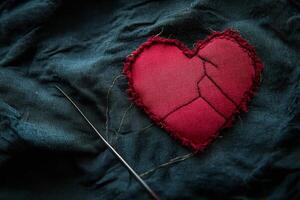 Red Fabric Heart with Stitching and Needle on Dark Textured Background for Creative Concepts photo