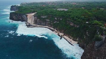 Construction and engineering on cliff coastline under Uluwatu temple in Bali. Drone view video