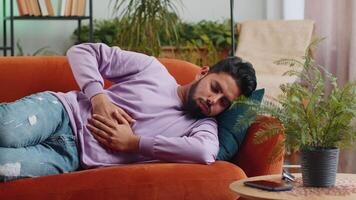 Indian man lying on sofa feeling sudden strong abdominal stomach ache, gastritis problem, diarrhea video
