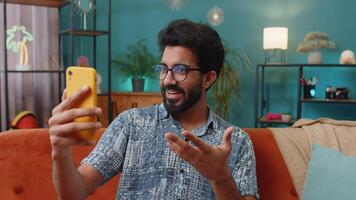 Indian man blogger taking selfie on smartphone recording vlog stories for social media subscribers video