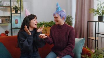 Lesbian women family celebrating birthday congratulating blowing burning candle on cake at home video