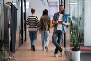 Senior bearded businessman, IT professional, trader, and crypto investor using a digital tablet in a modern coworking space. Tech-savvy professional working in an open office startup environment photo