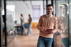 Senior bearded businessman, IT professional, trader, and crypto investor using a digital tablet in a modern coworking space. Tech-savvy professional working in an open office startup environment photo