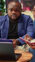 Black man and woman writing a report with information from notebook and archived files, improving networking skills and achieving career independence. Freelancers solving tasks. Camera A. video