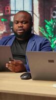 African american freelancers at home focused on online research and surfing the internet, utilizing a laptop and a tablet for telework and staying connected in a digital world. Camera A. video