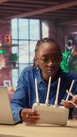 Black woman at home examines the modem and troubleshooting guide book, struggling to fix Wi Fi router and restore her internet connection for remote freelance tasks. Signal loss. Camera A. video