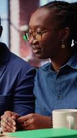 africano americano Pareja utilizando oído brotes a escucha a un podcast o atender un seminario web, escuchando el en línea discusión en un web plataforma. yo empleado hombre y mujer gastar hora a el escritorio. cámara b. video