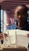 Black woman at home examines the modem and troubleshooting guide book, struggling to fix Wi Fi router and restore her internet connection for remote freelance tasks. Signal loss. Camera B. video