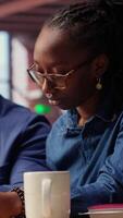 Worried African American woman looks at tax numbers on documents while her partner reassures her, helping with financial planning. Discussing ways to reduce expenses, save money. Camera B. video