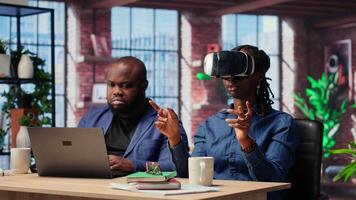Self employed couple navigates remote work with advanced technology, young man explores 3D simulations through a VR headset. AI, metaverse and innovation in modern careers. Camera B. video