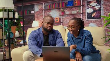 African american couple work on a management project for freelancing, using a laptop to research business trends and manage an online brand. Successful remote career development. Camera A. video
