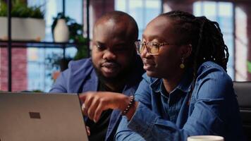 Black man and woman creating a report with online data from archived files, improving their skills and achieving career independence. Remote workers solving daily tasks. Camera B. video