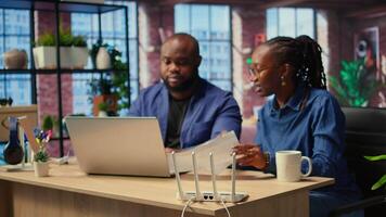 African American angry people struggling to work with internet lag issues, testing LAN cables and adjusting Wi Fi settings to restore connectivity. Displeased frustrated freelancers. Camera A. video