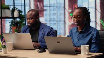 African american man and woman working remotely in their apartment, planning business strategies and discussing project development while using a laptop to track progress. Camera B. video